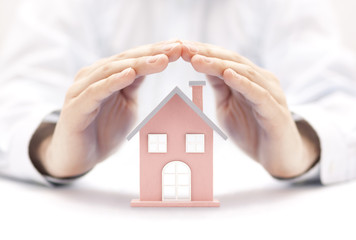 Poster - Property insurance. House miniature covered by hands. 