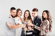 © Leika production - Company of friends in stylish casual clothes stand together and clink glasses with champagne on a white background and confiture around. Party time