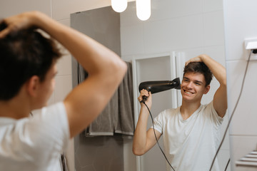 teenager using hairdryer in his bathroom