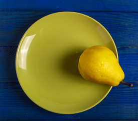 Pear on a red plate on the table. The view from the top.