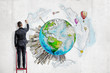© gearstd - A man in suit standing on a ladder and painting planet Earth with high-rise buildings springing up on it.