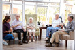 © Monkey Business - Male And Female Residents Sitting In Chairs And Talking With Carer In Lounge Of Retirement Home