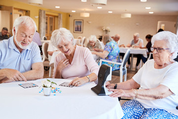 Group Of Seniors Playing Game Of Bingo In Retirement Home