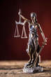 Lady Justicia holding sword and scale bronze figurine on wooden table