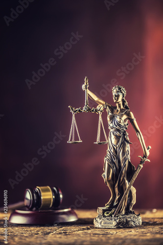 Lady Justicia holding sword and scale bronze figurine with judge hammer on wooden table