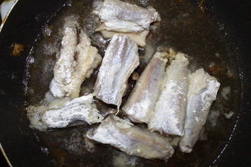 cooking fried fish in a pan