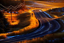 Old Country Road Turning Curved With Telephone Wires Glowing Golden Sunlight