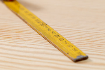 Yellow used yardstick on wooden background