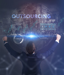 The concept of business, technology, the Internet and the network. A young entrepreneur working on a virtual screen of the future and sees the inscription: Outsourcing