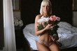 © sasamihajlovic - Girl in lingerie sitting on the bed and holding flowers