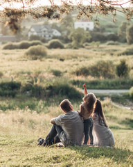 Young Adult Couple with Their Little Daughter Having Fun in the Park Outside the City, Family Weekend Picnic Concept, Three People Enjoying Summer Time