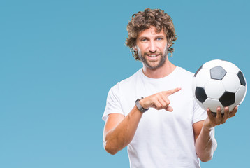 Canvas Print - Handsome hispanic man model holding soccer football ball over isolated background very happy pointing with hand and finger