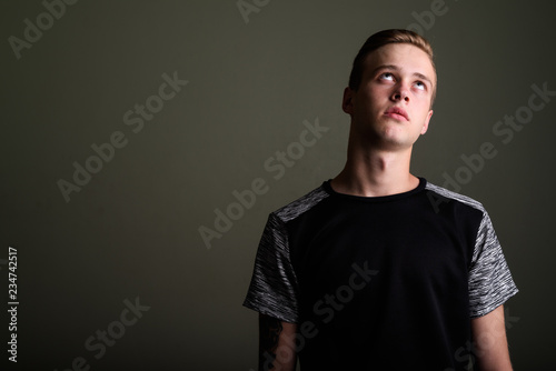 Fotografie, Obraz Young handsome man with blond hair against colored background