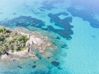 Drone aerial view of sea shore on stones and blue water