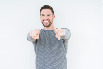 Young handsome man wearing casual sweater over isolated background Pointing to you and the camera with fingers, smiling positive and cheerful