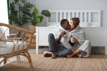 Wall Mural - happy loving couple drinking cocoa on winter morning in bed