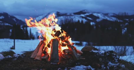 burning bonfire with winter mountains in background. slow motion. fairytale snow covered view with c