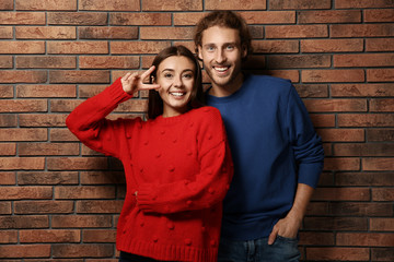 Canvas Print - Young couple in warm sweaters near brick wall