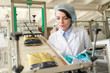 © Seventyfour - Portrait of young  woman controlling  packaging process at modern food factory and looking at macaroni bags sliding down conveyor belt, copy space