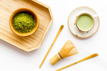 Wall Mural - Coffee and cocktails with matcha concept. Matcha latte near bowl with matcha powder and whisk on wooden tray white background top view copy space