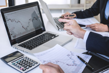 Poster - Business team two colleagues working with computer, laptop, discussing and analysis graph stock market trading with stock chart data, financial and investment concept