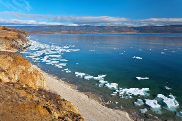 Lake Baikal at spring morning. Top view of the coast of the Olkhon Island and the Small Sea Strait with white ice floes on blue water