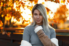 Portrait Of A Young Fashion Blonde Woman With Blue Eyes And Natural Make-up In A Stylish Knitted Sweater With Jacket At Sunset. Attractive Girl Outdoors On A Sunny Warm Autumn Day