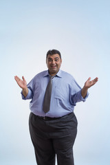 Portrait of smiling obese man in formal clothes standing with open palms on sides 