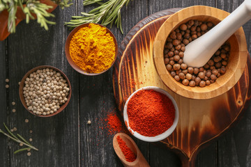 Bowls and mortar with different aromatic spices on wooden table