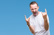 © Krakenimages.com - Middle age hoary senior man wearing white t-shirt over isolated background shouting with crazy expression doing rock symbol with hands up. Music star. Heavy concept.