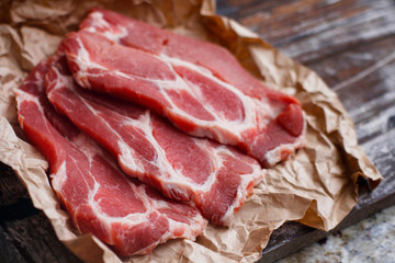 Fresh red chop meat on cooking paper. Dark red raw sliced meat on wooden table.