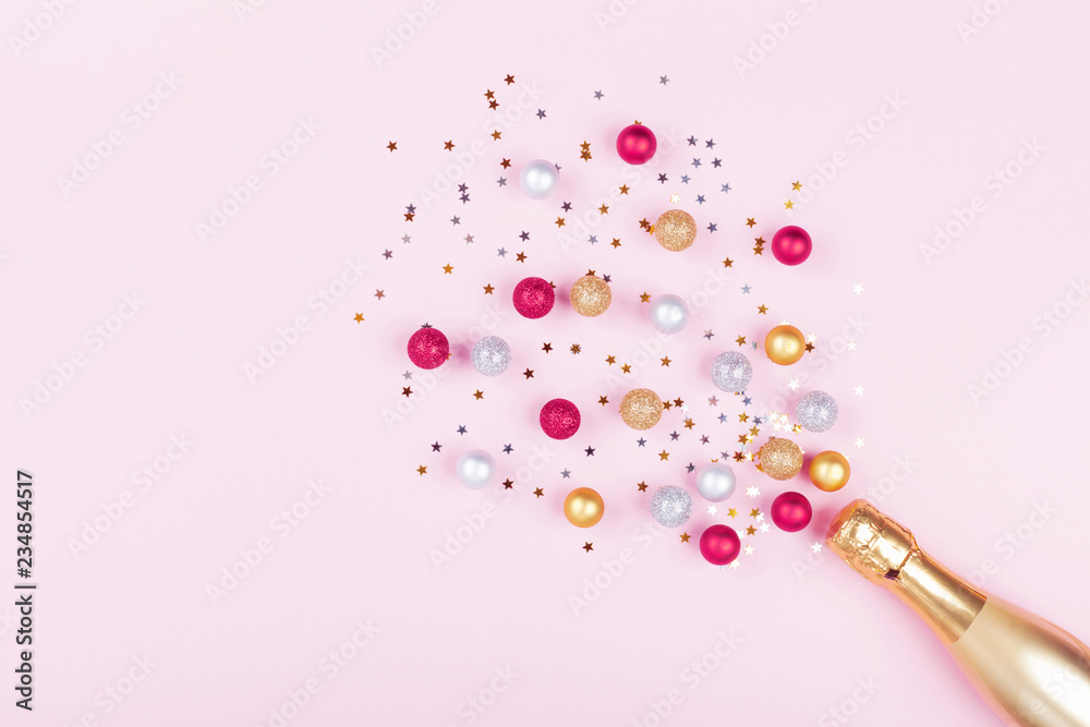Champagne bottle with confetti stars and holiday balls on pastel pink background. Christmas pattern. Flat lay style. - obrazy, fototapety, plakaty 
