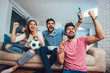 © Mediteraneo - Happy friends or football fans watching soccer on tv and celebrating victory at home.Friendship, sports and entertainment concept.