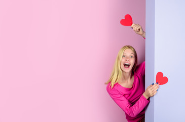 Valentine's Day. Beautiful woman with two paper hearts in hands. Happy girl on Valentine's day with hearts. Cute cheerful girl holds in hands paper heart. Blonde girl with red heart symbol. Copy space