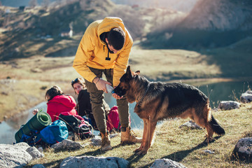 Poster - Group of people taking a break, relaxing during a hike. Man gives water to the dog