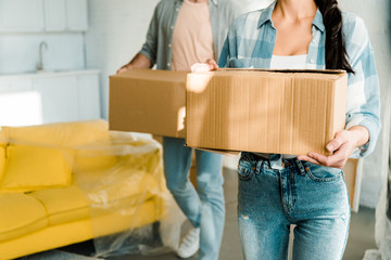 cropped view of husband and wife carrying cardboard boxes and packing for new house, moving concept