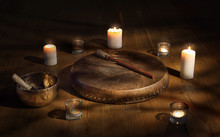 Shaman Tambourine And Tibetan Bowl Surrounded By Candles In A Dark Room.