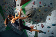 the girl hangs on the ledges climbing the wall in training room