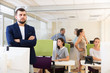 © JackF - businessman with arms crossed in busy modern coworking space