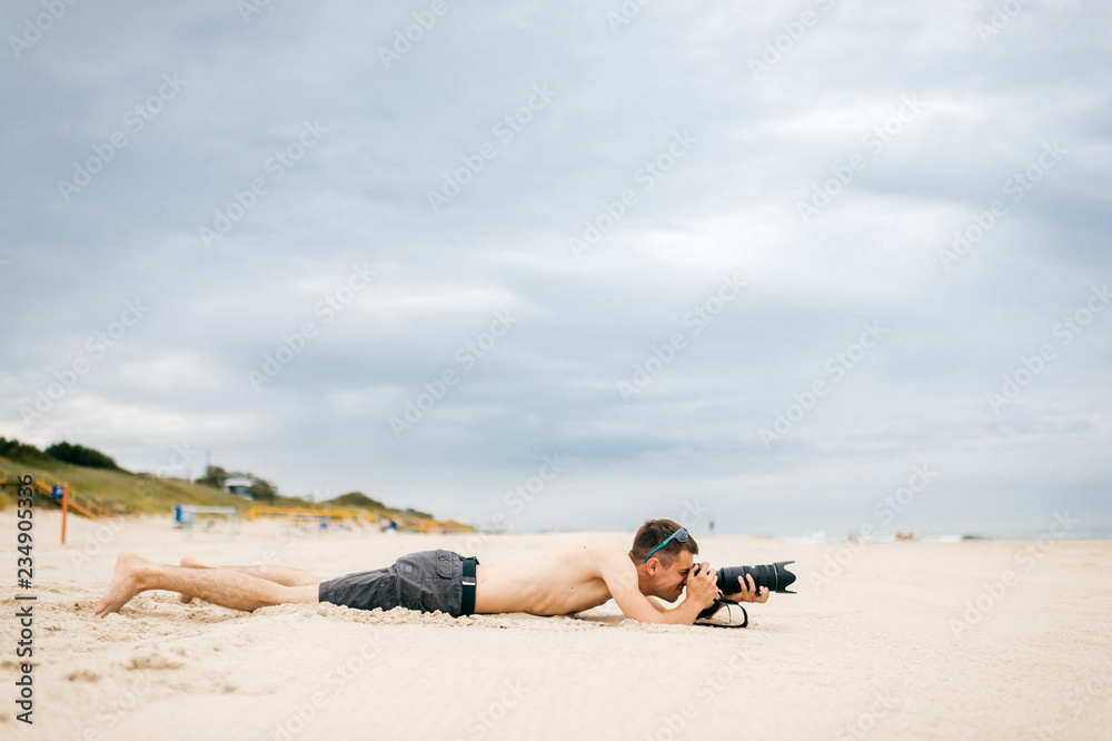 Young traveler man lying on beach near sea on vacation and making