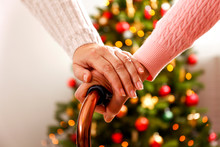 Elderly Woman Celebrating Christmas At Home, With Decorated Holiday Pine Tree On Background. Old Lady At Nursing Home. Close Up, Copy Space, Cropped Shot.