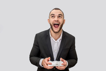 Happy young man stand and look up. He wears suit. Guy holds remote control. He is happy. Isolated on white background.