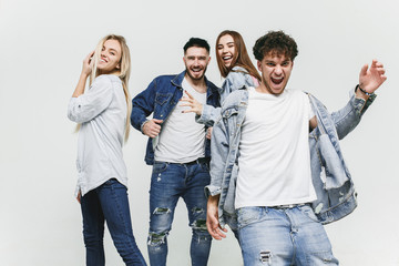 Group of smiling friends in fashionable jeans. The young men and woman posing at studio. The fashion, people, happy, lifestyle, clothes concept