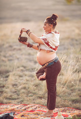 Wall Mural - concept. Woman playing a Tibetan bowl. Pregnant woman doing yoga in the field at sunset.