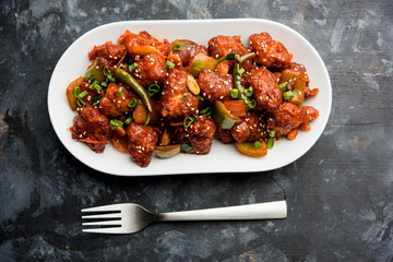 Indian Chilli Chicken dry, served in a plate over moody background. Selective focus