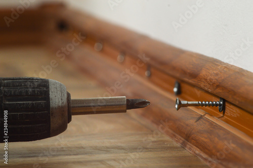 Fotografie, Obraz Repair work, with the help of a drill on the floor, installation of the plinth