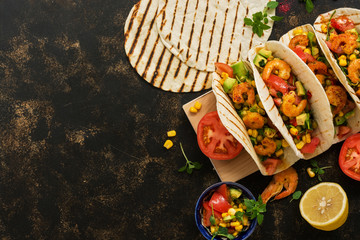 MEXICAN FOOD. Homemade tacos with shrimps and vegetables on a cutting board. View from above,overhead. Place for text.