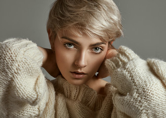 Portrait of young girl with blond hair wear sweather looking at camera isolated on gray background