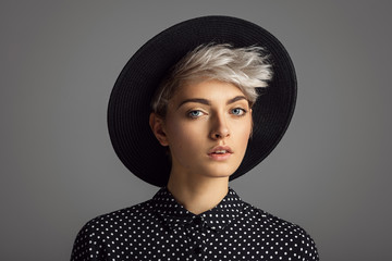 Wall Mural - Beautiful glamour portrait of young woman wearing black hat and polka dots shirt