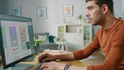 Handsome Software Engineer Works on a UX / UI Mobile App Template, Uses Personal Computer. Freelance Programmer Working from Cozy Living Room.